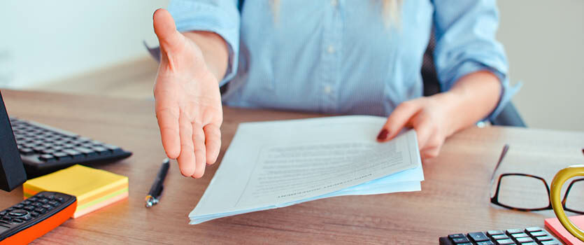 Frau am Schreibtisch reicht die Hand für einen Handschlag