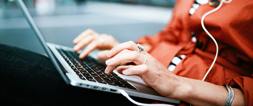 Oberkörper einer Frau mit einem Laptop auf dem Schoß