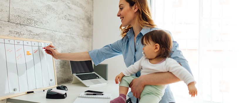 frau-traegt-termin-auf-board-ein-und-hält-ein-kleinkind-auf-den-arm