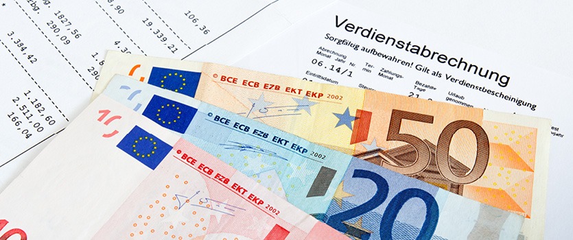 Eurogeldscheine und eine Verdienstabrechnung liegen auf dem Tisch