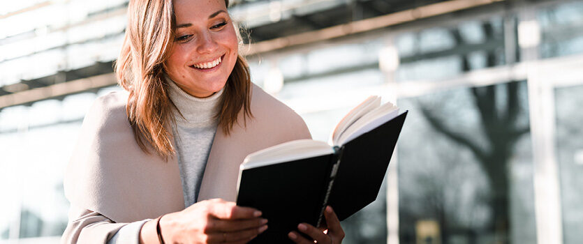 Junge Frau liest draußen ein Buch