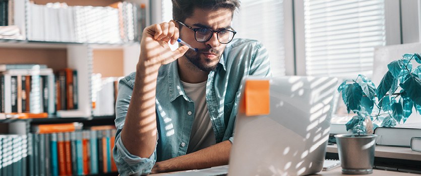 Unsicherer junger Mann in einer Bibliothek