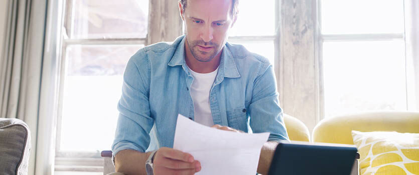 Mann liest seinen neuen Arbeitsvertrag im Wohnzimmer