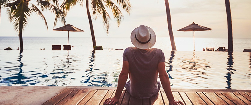 Mann genießt Urlaub am Swimmingpool und Palmen