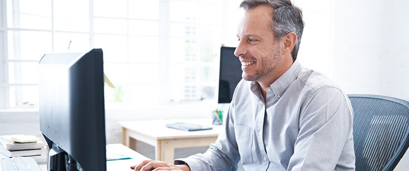 Reifer Mann arbeitet im Büro am Computer