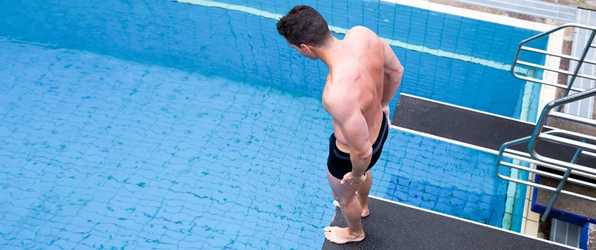 Mann im Schwimmbad auf einem Sprungturm
